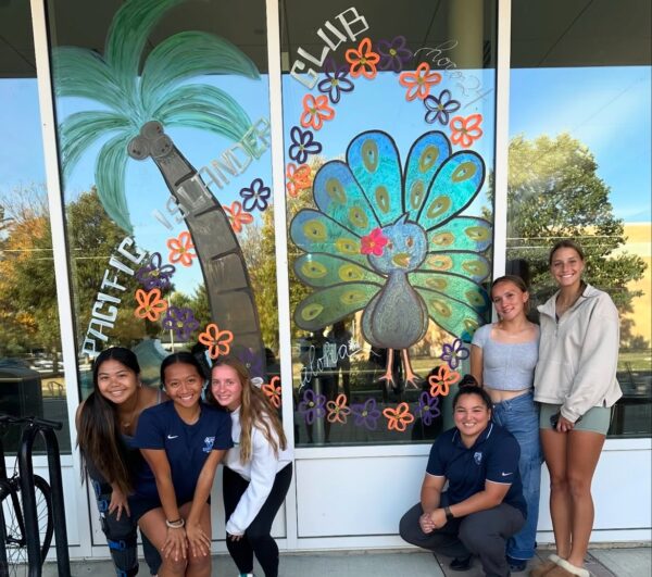 A group of UIU students pose in front of a decorated window during the homecoming celebration