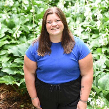 Photo of Athena Hansen outside with a patch of green plants in the background