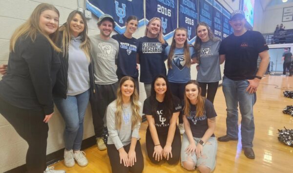 Cheer and dance alumni's standing for a picture in the gym.