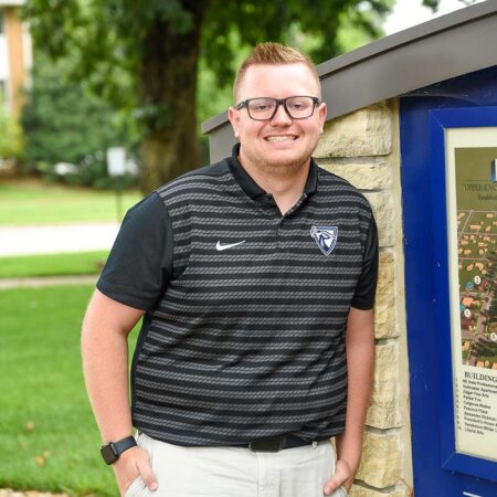 Photo of Cody Lawrence outside next to a stone campus map kiosk