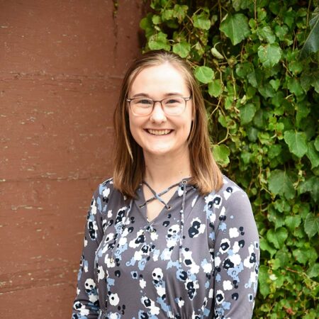 Photo of McKenna Massman in front of a brick wall with ivey