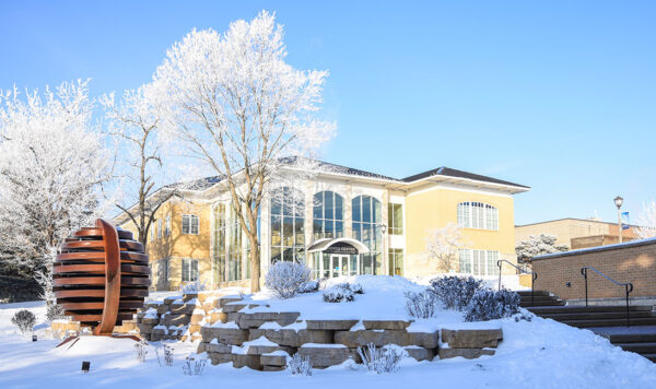 UIU's Andres Center for Business & Education, a limestone building in winter with blue sky and snow-covered foreground