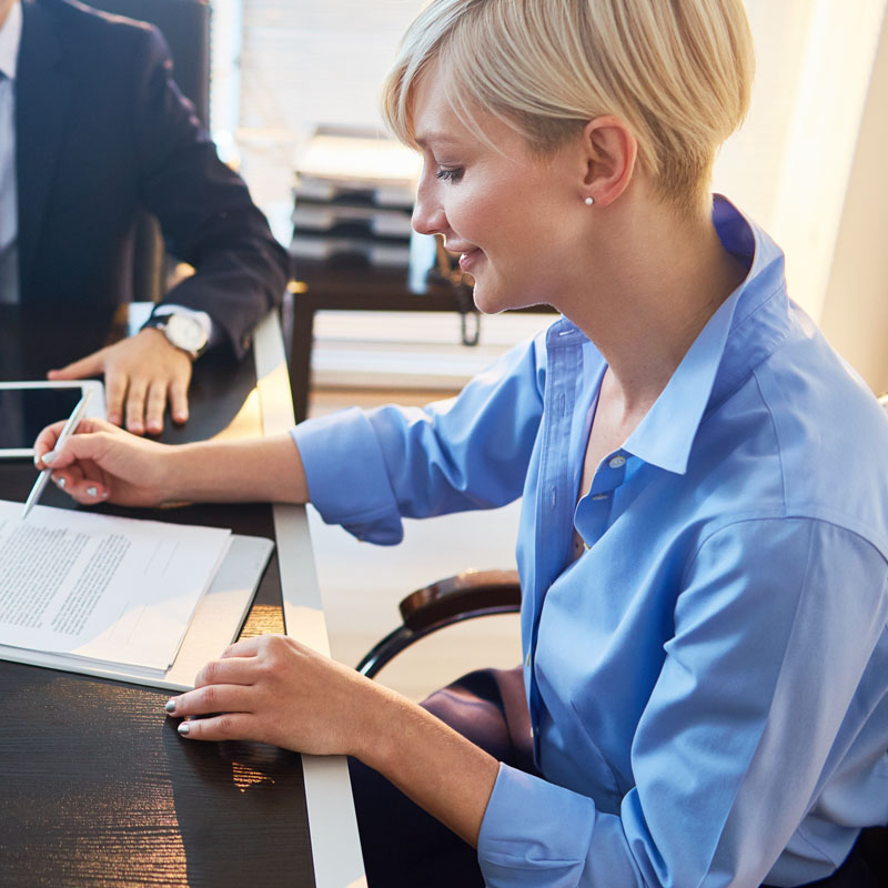 Business associates gather around a table to sign contracts