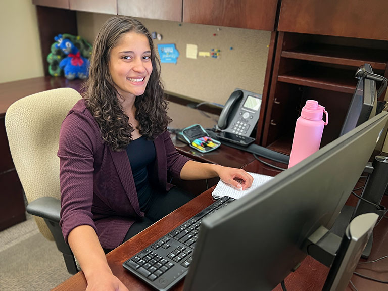 A UIU student working in an offices in front of a display and keyboard