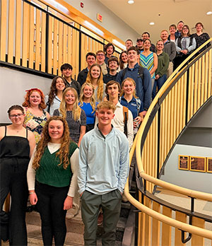A group of over 20 UIU ExcEL Scholars pose for a photo on a curving staircase