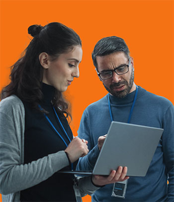 Two standing people huddle around a laptop