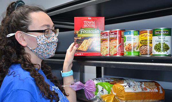 Student placing free food items into pantry