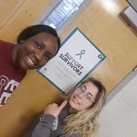 two students pose by support survivors sign