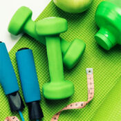 Fitness equipment, measuring tape and apple on an exercise mat