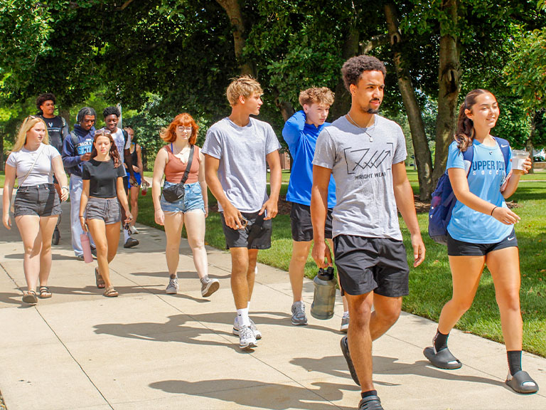 A large group of UIU students walking on Fayette campus on a sunny day