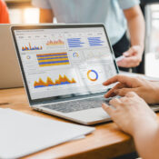 An analytst works at a laptop displaying charts and graphs