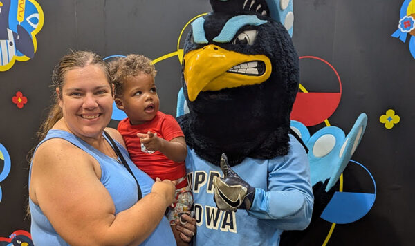 People smile for a photo with Pete, a large peacock mascot