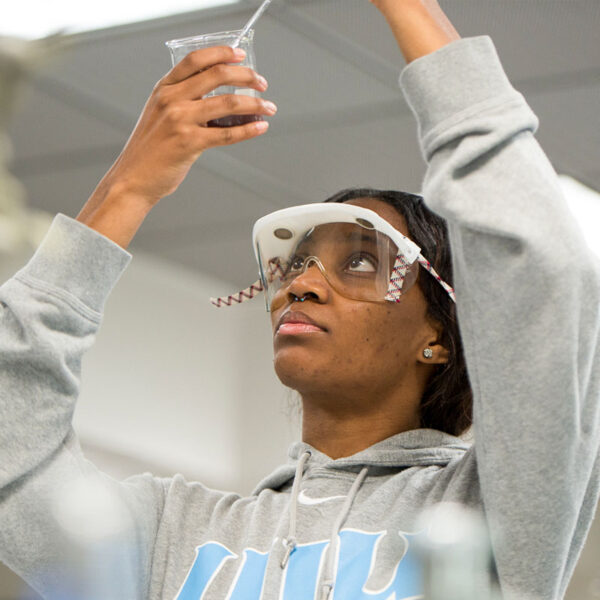 UIU student in a lab using a pipette to do an experiment.