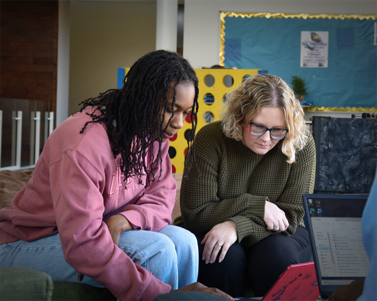 A student and staff member work side by side in a study lounge