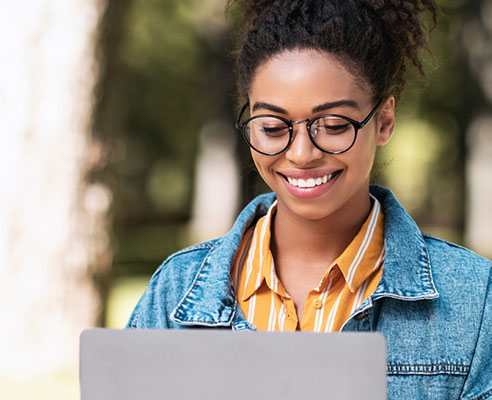 Young woman with glasses using a laptop outdoors