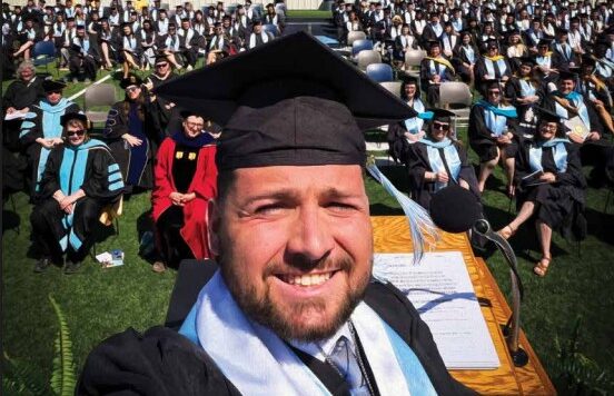 UIU Bridge magazine cover featuring a photo of a smiling graduate dressed in cap and gown snapping with a large crowd of graduates and spectators in the background.