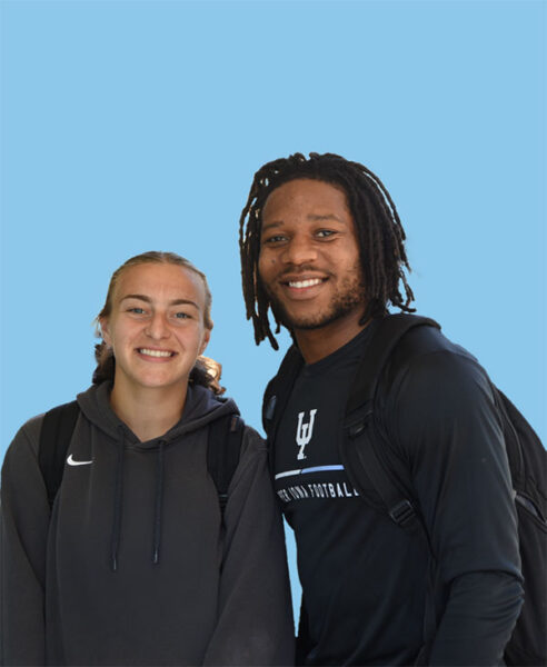 Two UIU students pose for a photograph on a light blue background