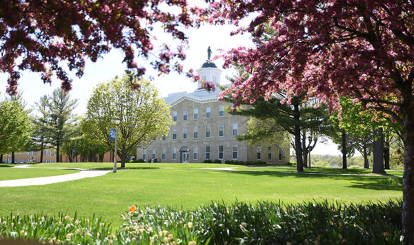 Photo of UIU's Alexander Dickman Building with blossoming trees and a green lawn in the foreground