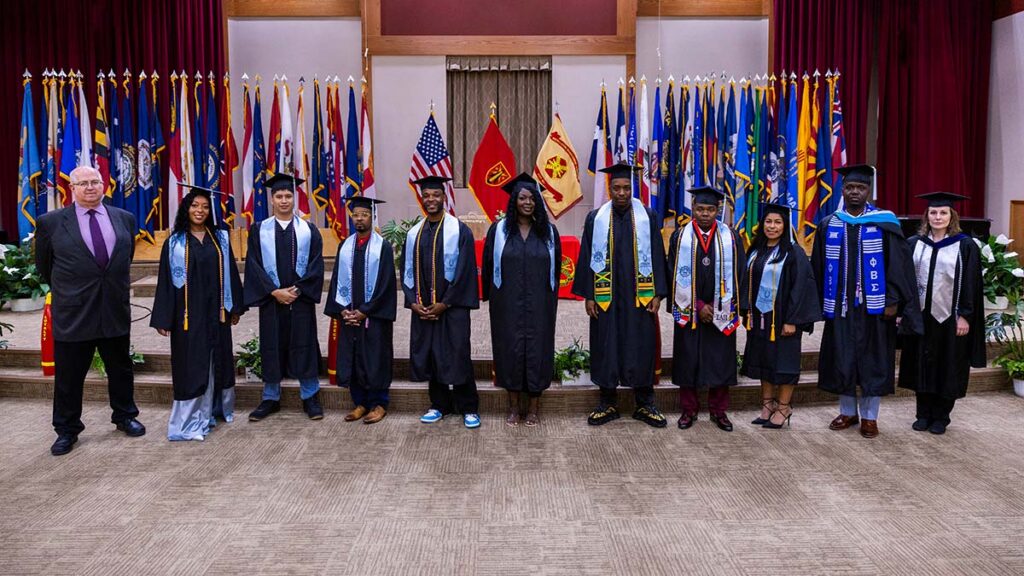 A group of graduates dressed in graduation regalia pose for a photo