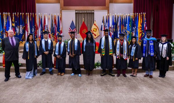 A group of graduates dressed in graduation regalia pose for a photo